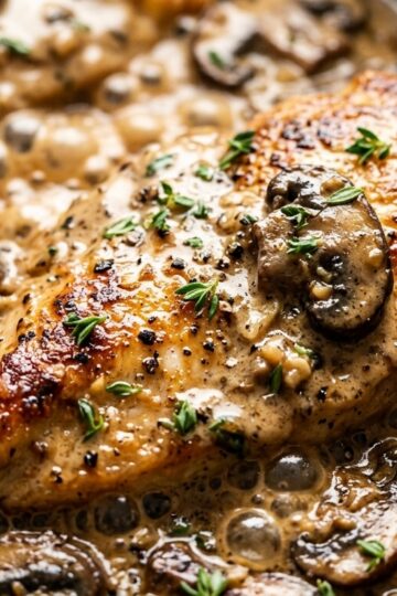 Ultra close-up macro of golden seared chicken cutlet smothered in creamy garlic parmesan mushroom sauce with fresh parsley and melted cheese