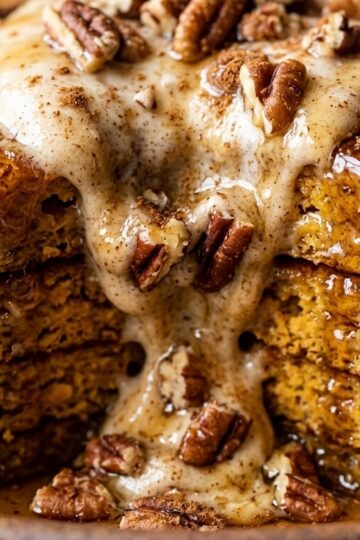 Ultra close-up macro of a tall stack of fluffy golden pumpkin spice pancakes with dripping maple syrup and melting butter