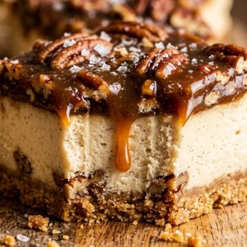 Ultra close-up macro of salted caramel pecan cheesecake bar with buttery crust, velvety cheesecake, and dripping caramel pecan praline