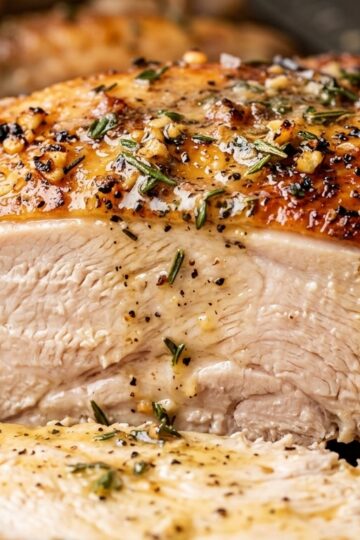 Ultra close-up macro of juicy garlic herb butter roasted turkey breast with golden crispy skin