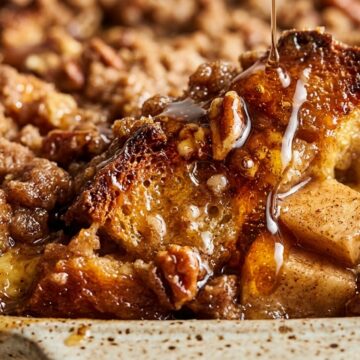 Ultra close-up macro texture of baked apple cider french toast casserole with custard-soaked brioche, caramelized apples, brown sugar pecan streusel, and spiced cider glaze