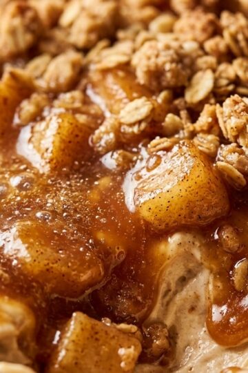 Ultra close-up macro texture of warm caramel apple crisp cheesecake dip with bubbling amber caramel, spiced apples, and oat streusel