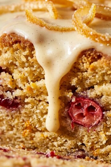 Ultra close-up macro slice of moist cranberry orange pound cake with dripping cream cheese glaze