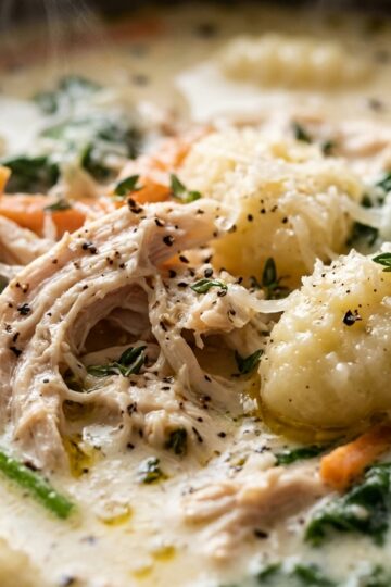 Ultra close-up macro of creamy chicken and gnocchi soup in rich garlic herb cream broth