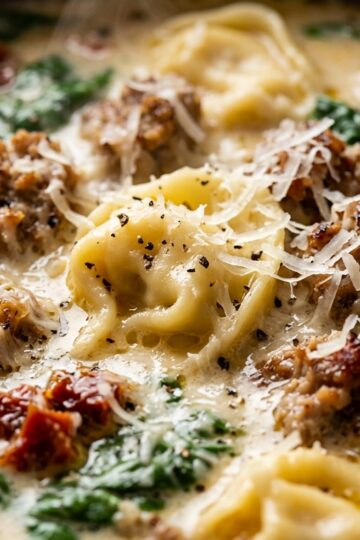 Steaming creamy parmesan sausage and tortellini soup with spinach and sun-dried tomatoes
