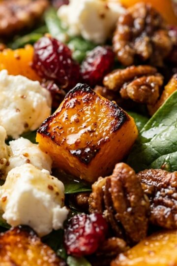 Warm roasted butternut squash and goat cheese salad glistening with maple Dijon cider dressing