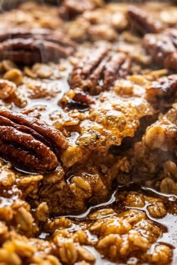 Ultra close-up macro texture of warm freshly baked spiced pumpkin pecan baked oatmeal with caramelized pecans, pumpkin spice, and glistening maple syrup