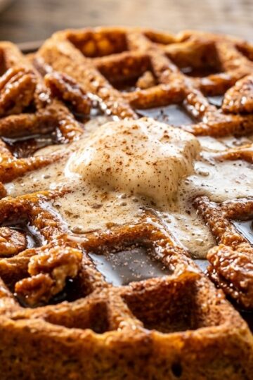Ultra close-up macro of crispy spiced pumpkin Belgian waffles with dripping maple syrup and cinnamon butter